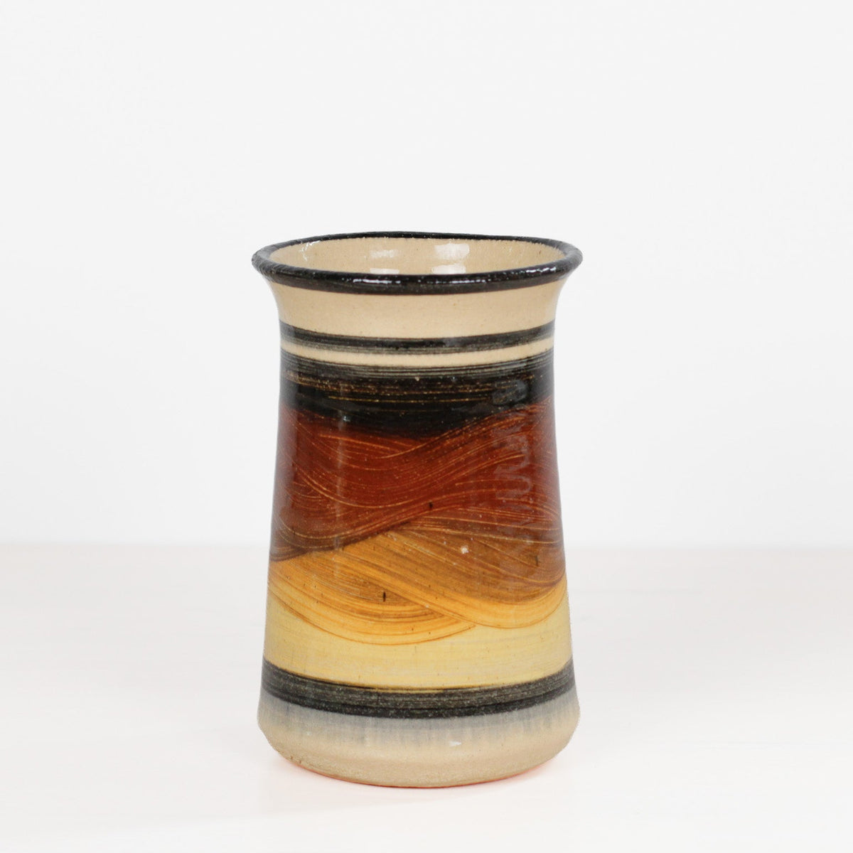 A handmade ceramic vase with a flared rim, featuring a marbled pattern of brown, orange, beige, and black bands, set against a plain white background.