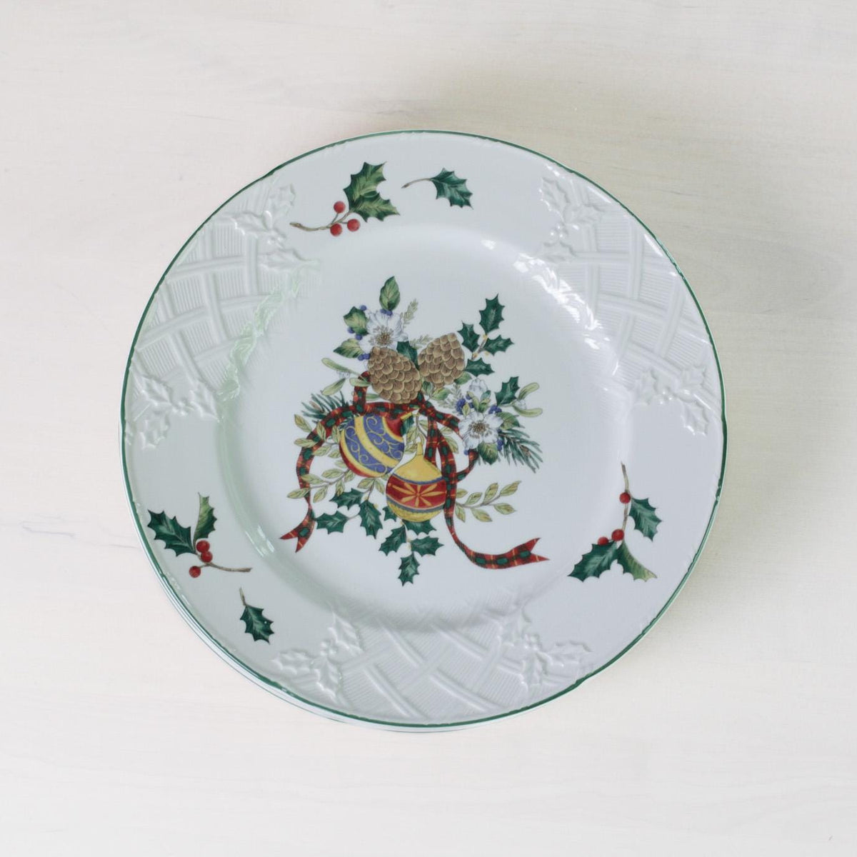 Decorative plate with a coat of arms and holly design on a white background