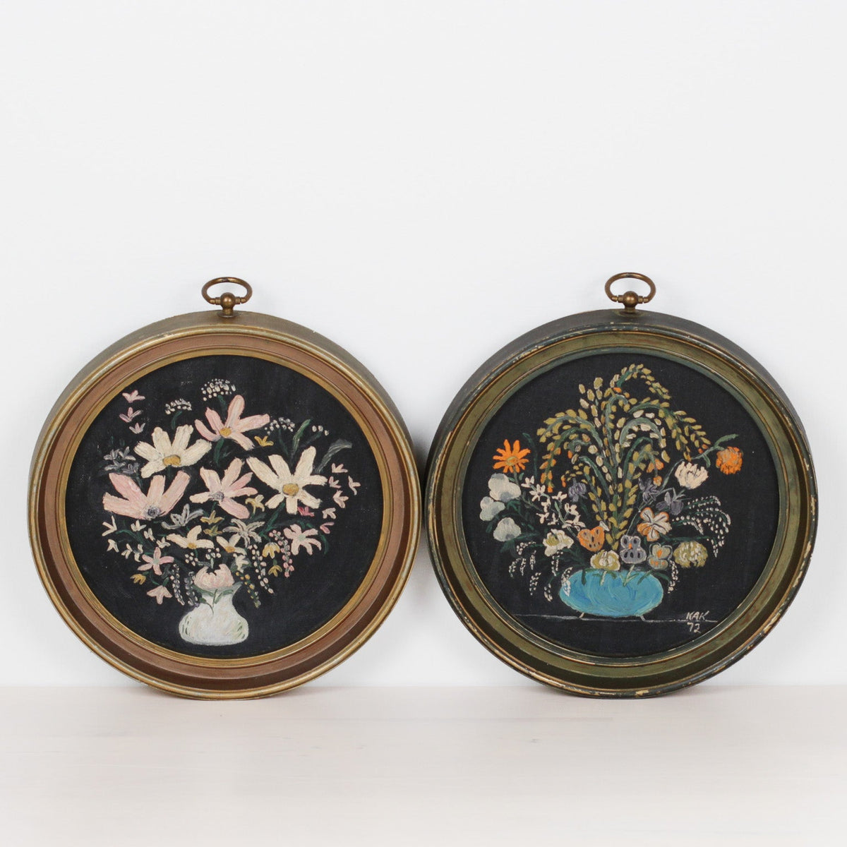 Two round framed needlework panels depicting floral bouquets on a white background.