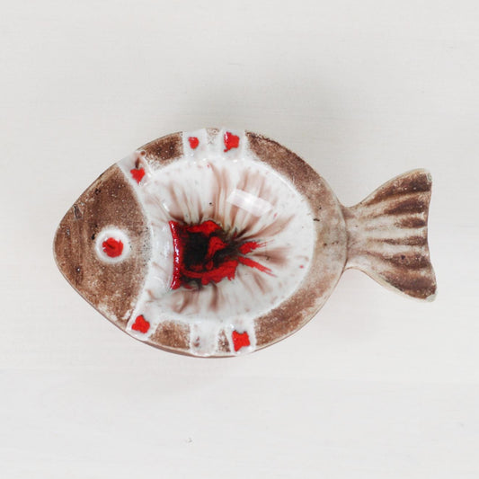 A ceramic fish-shaped dish with a brown and white glaze and red accents, photographed from above on a white background.